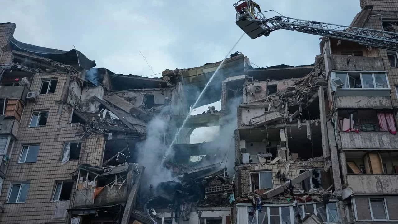 Russia Ukraine Missile Attack: Russia Ukraine Missile Attack aftermath in Kyiv showing damaged residential buildings, rescue teams, smoke rising after ballistic missile and drone strikes before the NATO Summit.