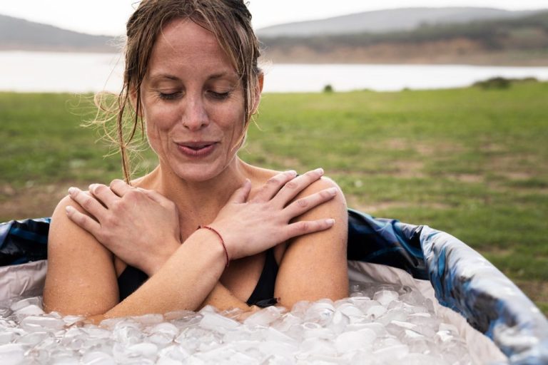 Woman taking an ice therapy cold plunge in an ice-filled tub